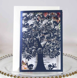 Detail of laser-cut tree and owl design on deep blue pearlescent paper invitation card
