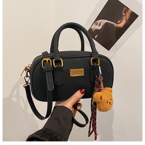 Detail of black matte bowling bag with golden logo plate and cute bear charm accessory