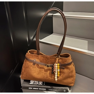 Detail of vintage brown suede shoulder bag with beaded charm and leather buckle trim