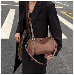 Detail view of deep brown cylinder crossbody bag in premium suede with leather straps
