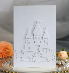 Intricate laser-cut white wedding invitation card with European castle and carriage design