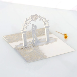 Macro shot of silver glittery laser-cut wedding invitation featuring a couple silhouette