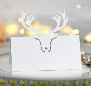 Close-up of white laser-cut reindeer place card on a gold-rimmed ceramic plate