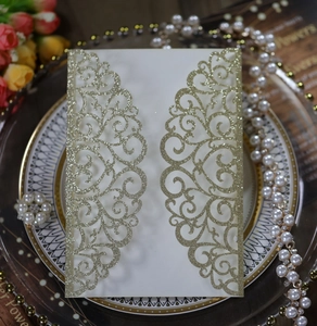 Detail of laser-cut glitter wedding invitation with champagne gold floral vine patterns