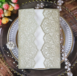 Detail of laser-cut floral pattern on golden glitter wedding invitation with bi-fold design