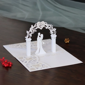 Close-up of 3D laser-cut wedding card featuring a couple under a heart-shaped floral arch