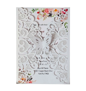 Detail view of laser-cut butterfly lace pattern on white pearlescent wedding invitation