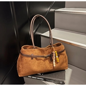 Detail of vintage brown suede tote bag with leather strap and beaded charm on stairs
