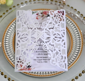 Close-up of laser-cut wedding invitation featuring intricate floral vines and a heart pattern