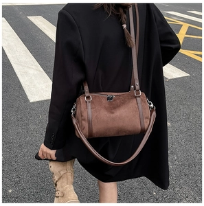 Close-up of a dark brown vintage suede Boston bag with silver zippers and leather straps