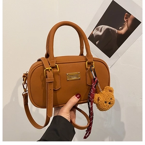 Close-up of caramel retro bowling bag with double handles and cute teddy bear pendant