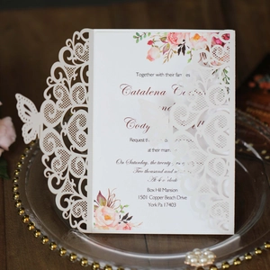 Close-up of laser-cut butterfly lace wedding invitation with floral inner card detail