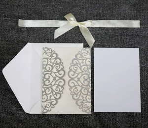 Close-up of laser-cut silver glitter wedding invitation set with white ribbon bow