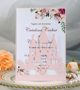 Macro detail of laser-cut pink castle and carriage wedding invitation with floral insert