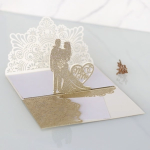 Dettaglio dell'invito di nozze glitter oro tagliato al laser con silhouette Mr & Mrs