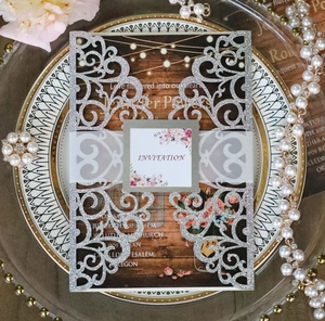 Close-up of laser-cut silver glitter wedding invitation with pink floral details