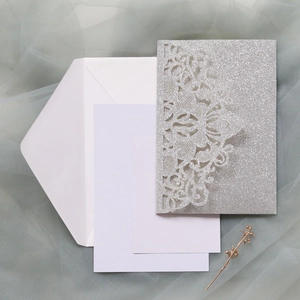Vue macro de l'invitation de mariage en dentelle argentée découpée au laser avec enveloppes