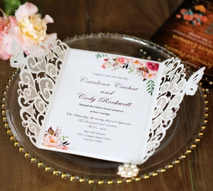 Detail of laser-cut wedding invitation with lace floral patterns and golden accents