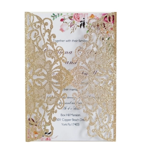 Detail of laser-cut gold glitter invitation cover featuring intricate floral vine patterns