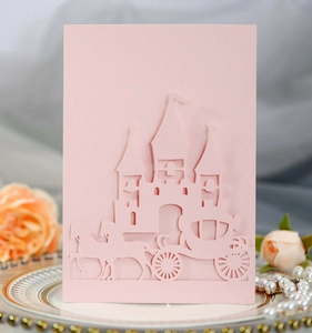 Macro shot of laser-cut castle and carriage wedding invitation card on pearl background