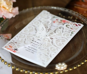 Detail of laser cut lace wedding invitation with white 3D butterfly and floral inner card