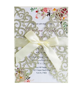 Detail of laser cut glitter wedding invitation with champagne cover and satin ribbon bow