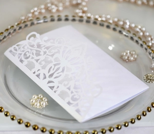 Detailed laser-cut hollow lace wedding invitation on a luxury decorative glass tray