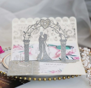 Intricate laser-cut 3D silver glitter wedding invitation with floral heart arch detail