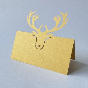 Detail of laser-cut reindeer place card in gold pearlescent paper for wedding table decor