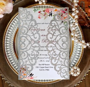 Close-up of laser-cut silver glitter wedding invitation with floral insert card