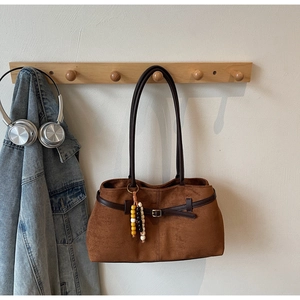 Detail of vintage brown suede tote bag featuring colorful wooden bead charm and long straps
