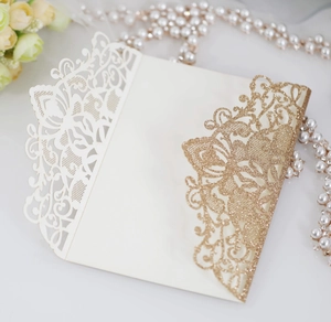Macro shot of glitter gold laser-cut butterfly and flower pattern on wedding invitation