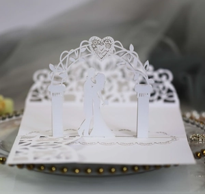 Macro detail of laser-cut 3D wedding invitation featuring a romantic couple under a heart arch