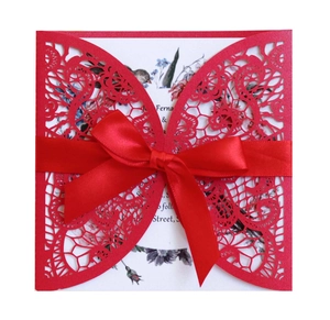 Detail of red laser cut butterfly wedding invitation with elegant silk ribbon bow
