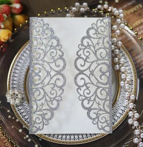 Detailed close-up of cream laser-cut wedding invitation sleeve with silver glitter finish