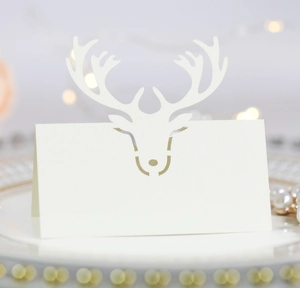 Macro detail of laser-cut white pearlescent reindeer place card for holiday table setting