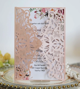 Detail of laser-cut lace floral pattern on rose gold wedding invitation card