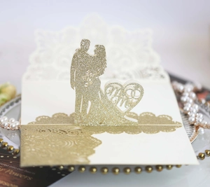 Dettaglio dell'invito di nozze 3D tagliato al laser con glitter dorati e sagoma Mr & Mrs
