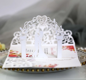 Macro view of laser-cut 3D wedding invitation featuring a kissing couple silhouette