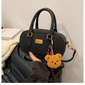 Detail of black bowling bag featuring golden metal plate and a cute teddy bear charm