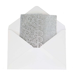 Macro detail of laser-cut lace wedding invitation with silver glitter finish and envelope