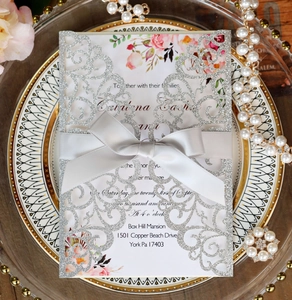 Detailed laser-cut silver glitter wedding invitation with floral insert and grey ribbon bow