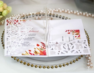 Close-up of elegant laser-cut lace floral pattern on pearlescent white wedding invitation