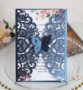 Detail of laser-cut wedding invitation with butterfly ornament on glass tray
