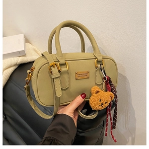 Detail of dark green bowling bag featuring gold metal plaque and cute bear charm accessory