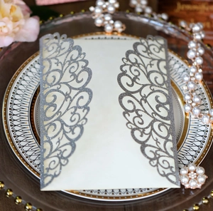 Detail of silver glitter laser cut wedding invitation with intricate floral hollow design