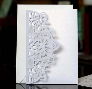 Detail of laser-cut floral lace wedding invitation set with pearlescent white paper texture