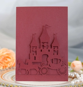Detail of laser-cut burgundy invitation featuring intricate castle and carriage patterns