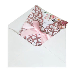Detail of rose gold glitter laser-cut wedding invitation with pink satin bow and floral insert