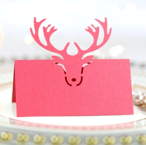 Laser-cut red reindeer place card with pearl finish on festive dining table setting